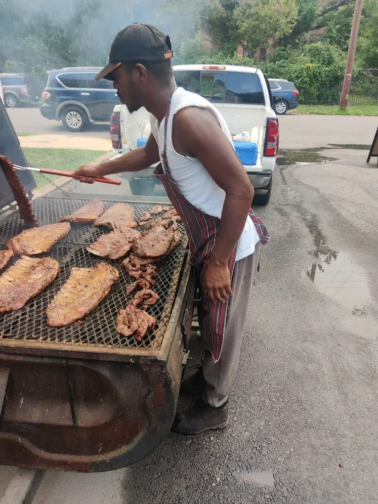 Food-truck vendor grilling skewered meats at the curb outside the von C Brewing Co. taproom in Norristown PA — open flame visible, prep counter set up at chest height, beer-garden guests queued for service